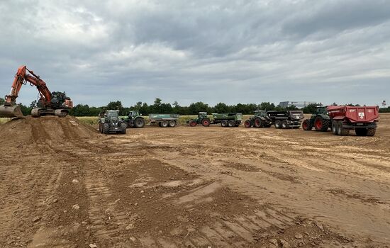 Mehrere Trecker beim beladen durch einen Bagger mit Erde