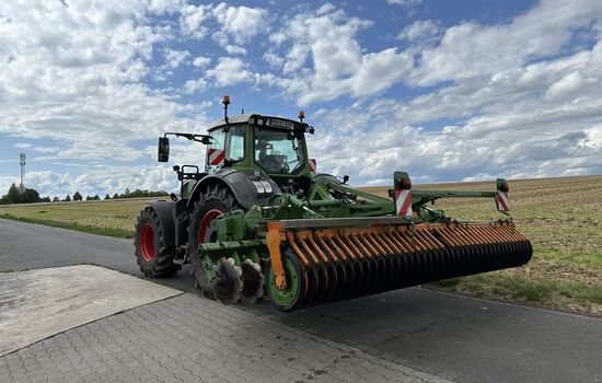 Trecker mit Heckanbau Disc Walze fährt vom Bauernhof