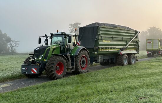 Trecker mit Anhänger steht auf einem Feldweg