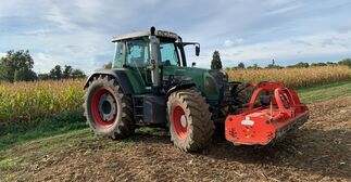 ein Traktor mit einem frontanbau Mulcher steht auf dem Feld