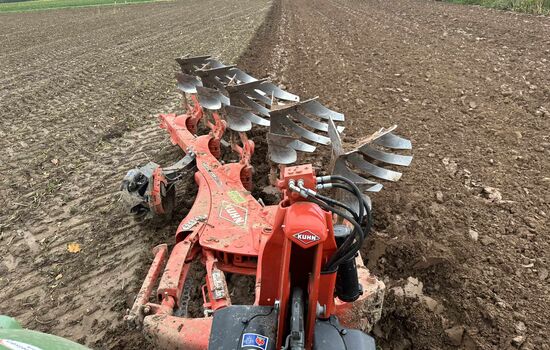 Blick aus dem Traktor auf den Wendepflug bei der Arbeit auf dem Acker