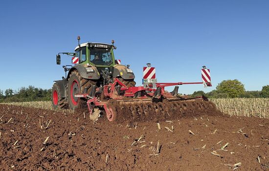 ein Traktor mit angebauter DISC-WALZE auf dem Acker bei der Arbeit von hinten gesehen