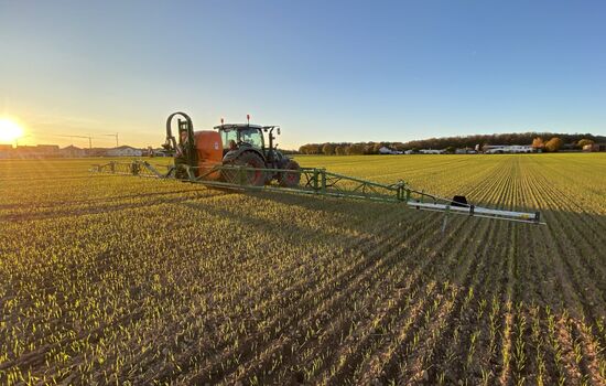 Feld wird durch einen Trecker mit Anbau Sprüher gedüngt