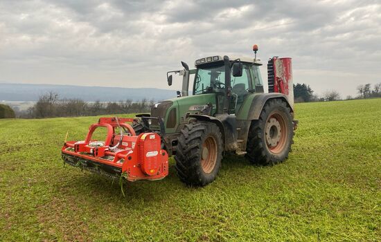 ein Traktor mit einem front- und heckanbau Mulcher fährt auf dem Feld