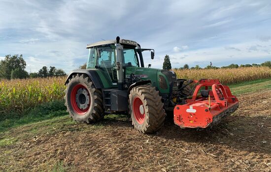 ein Traktor mit einem frontanbau Mulcher steht auf dem Feld